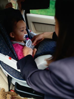 A mother fastens her daughter in a car seat in this 2003 file photo