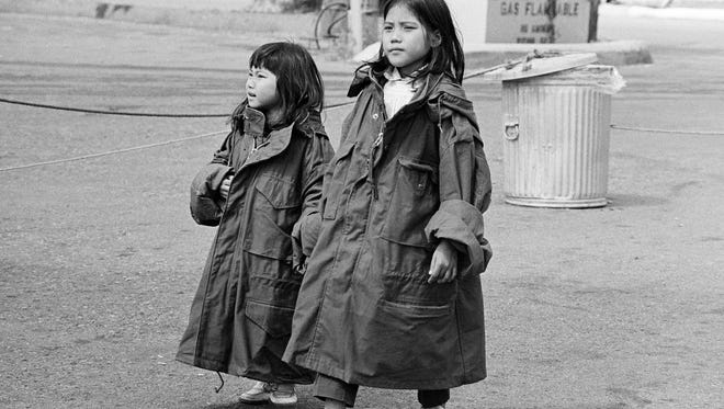 Two young Vietnamese refugees wear oversized GI issue coats as they stroll the streets of their tent-city at the Camp Pendleton Marine Corps base in Southern California on May 7, 1975.