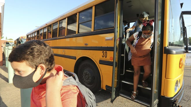 Corinth Elementary School students exit their bus wearing their Masks as they arrive for their first day back to school on Monday morning July 27.]AP Photo/Northeast Mississippi Daily Journal, Adam Robison]