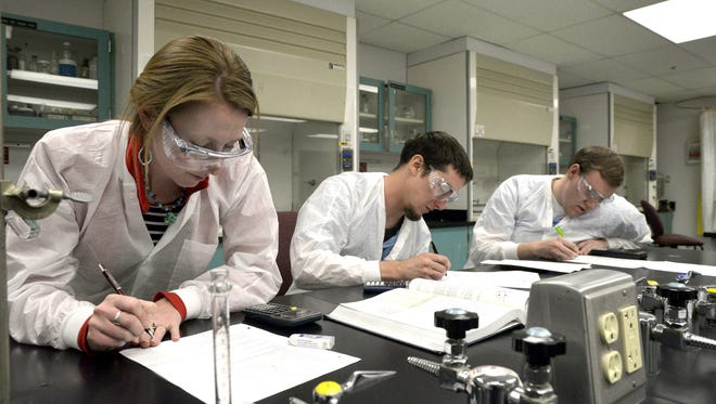 Gretchen Gray, left, Christopher Reece and Devin Signs, work together Nov. 5, 2014, during a science lab for an introduction to chemistry class at San Juan College in Farmington.