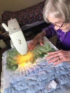 Fabric artist Wilma Schmidt works on quilting a piece of art used to illustrate the Circle of the Seasons book on which she collaborated with fellow Kidron Bethel Village resident and children's book author Laurel Gugler. The book is available for purchase at local businesses and online.
