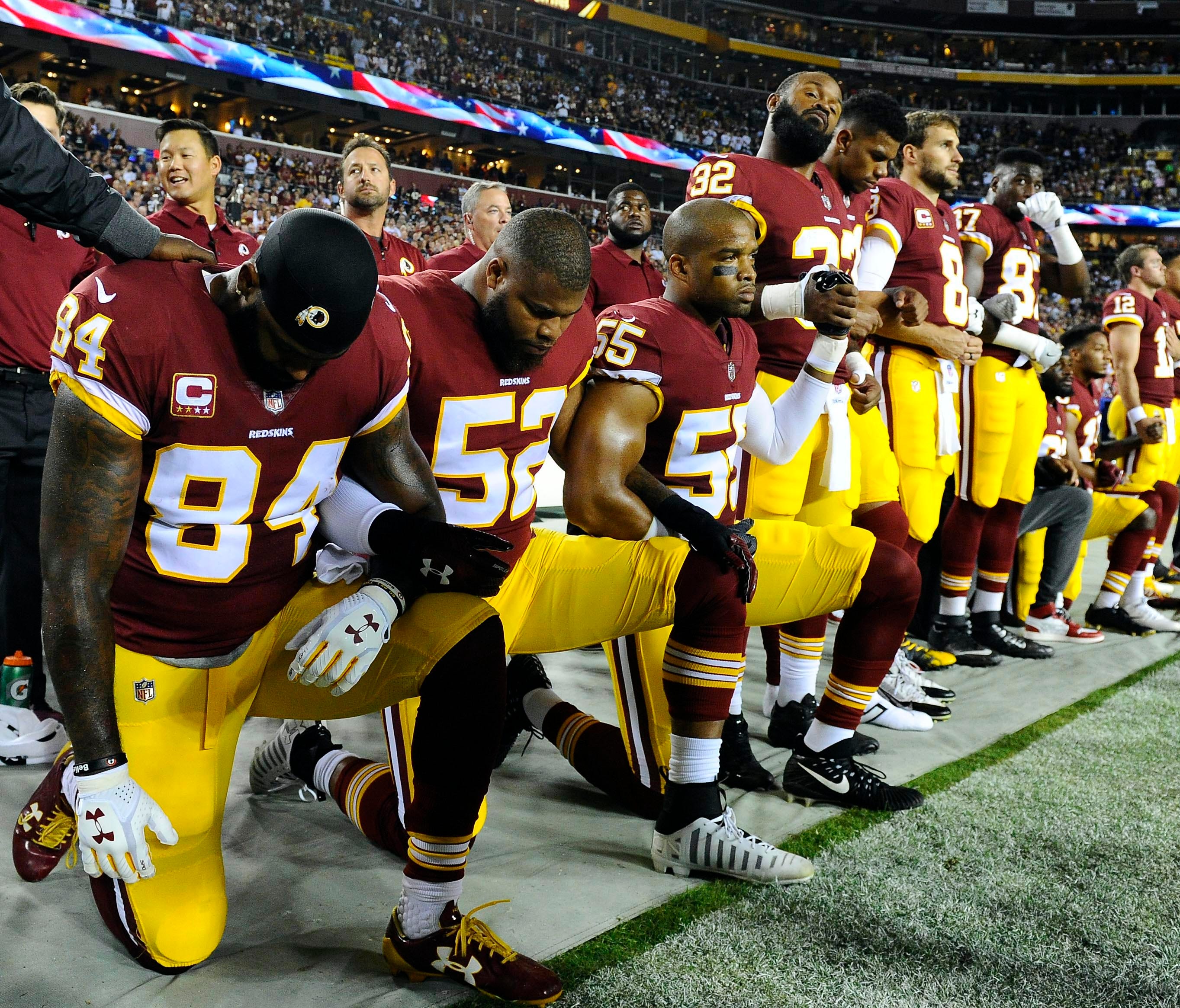 Washington Redskins tight end Niles Paul (84) and linebackers Ryan Anderson (52) and Chris Carter (55) kneel with teammates during the playing of the national anthem before the game against the Oakland Raiders at FedEx Field.