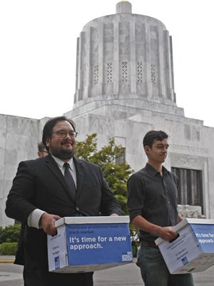 Anthony Johnson (left), chief petitioner for New Approach Oregon, gets help in bringing the last of over 140,000 signatures supporting a ballot initiative to legalize recreational marijuana use from the Capitol and to the election division of the Secretary of State's office on Thursday, June 26, 2014.