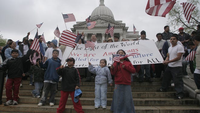 In this 2006 file photo, immigrants chant and wave American flags on the steps of the capitol building in Madison.