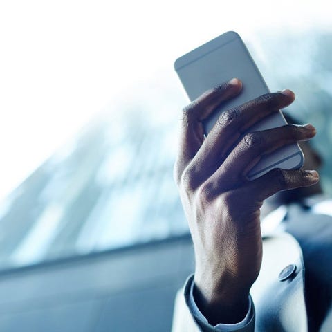 Hand holding a smartphone, with a building out of 
