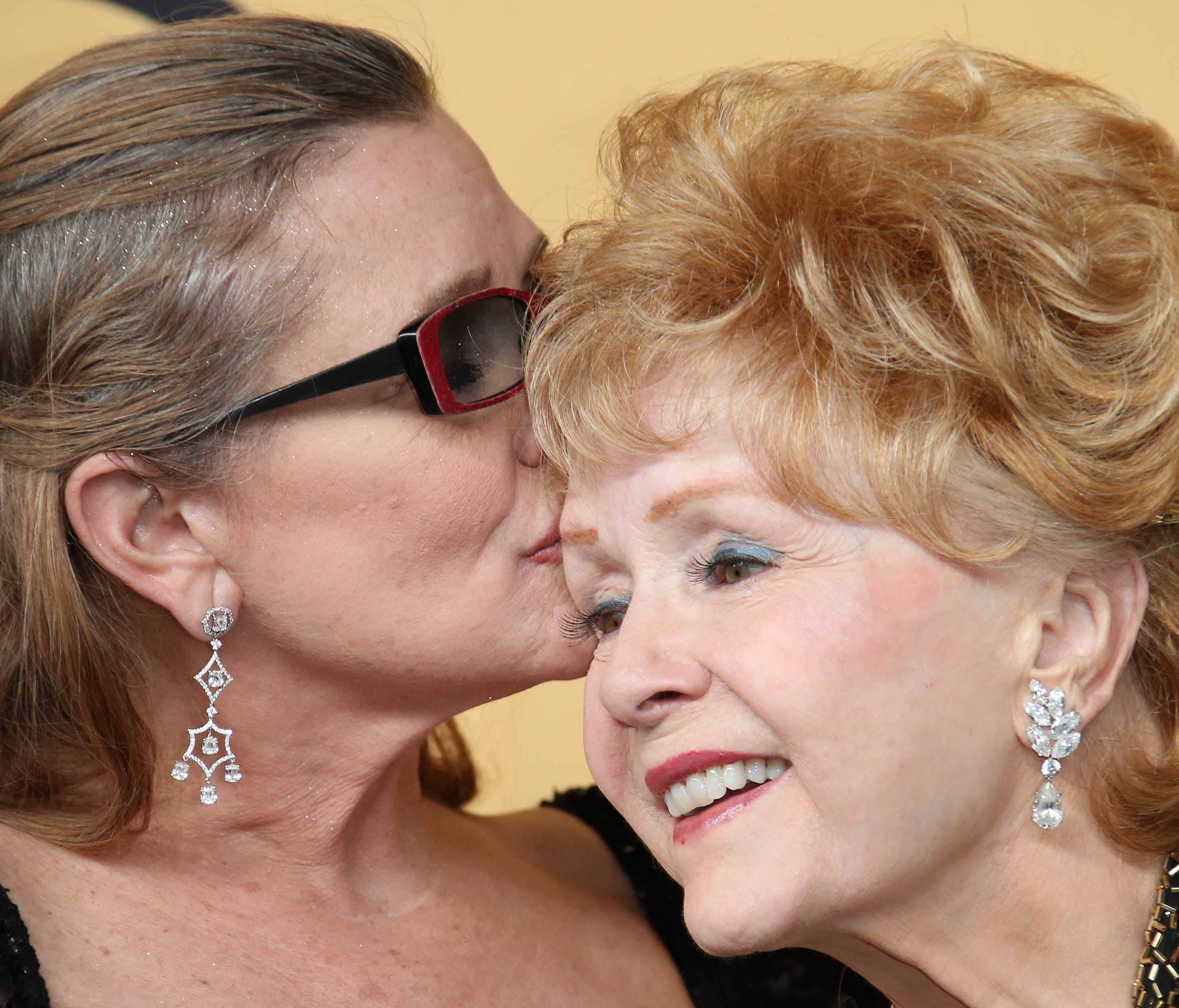 Carrie Fisher gives a kiss to her mother,  Debbie Reynolds, in the photo room of the 20th Screen Actors Guild Awards in January 2015.