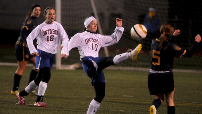 Ontario's Rachel Miller (10) kicks the ball away from Brittney Seitz of Norwalk while Ontario teammate Amanda Nething (16) looks on during last year's district tournament in girls soccer at Ashland High School.