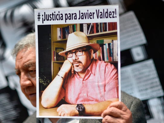A journalist shows a picture of Mexican journalist
