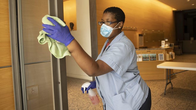 Custodian Shaunte Williams disinfects high-touch areas at the Harry Ransom Center at the University of Texas. Williams is one of 450 custodians who are going to be regularly disinfecting the 430-acre campus when students return at the end of the month.