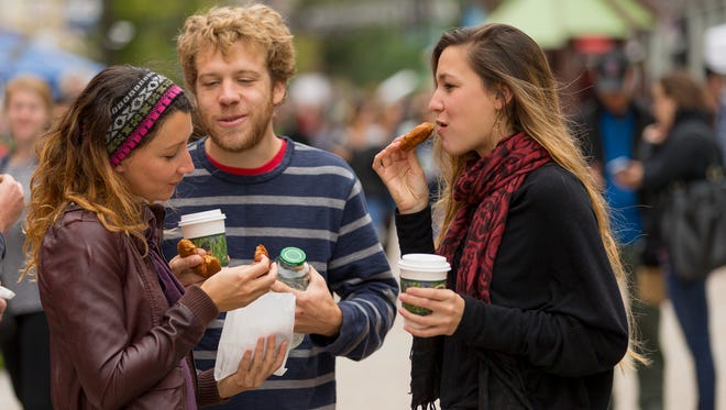 From left, Rochelle Kingsbauer and Matty Marshall, of Ithaca, talk with Kingsbauer's sister, Rosalie, of San Diego, California, as they eat apple cider doughnuts Friday at the Apple Harvest Festival on the Commons in Ithaca.