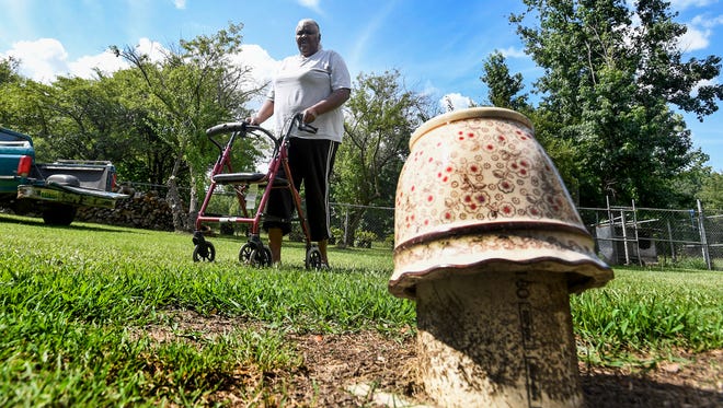 Charlie Mae Holcombe walks past the cover to her septic tank at her home in Hayneville, Ala. on Friday July 6, 2018. She has had decades of flooding and sewer problems at her home.