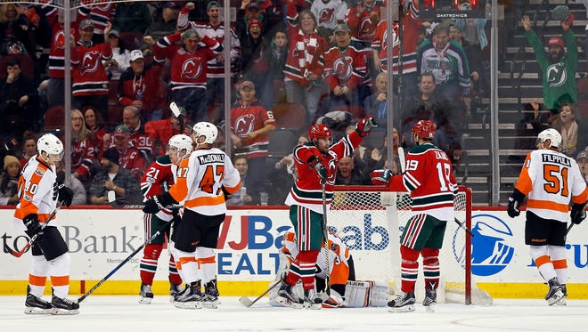New Jersey Devils center Adam Henrique (14) celebrates scoring a goal past Flyers goalie Michal Neuvirth (30) with Devils center Travis Zajac (19) during the third period of Thursday's game.