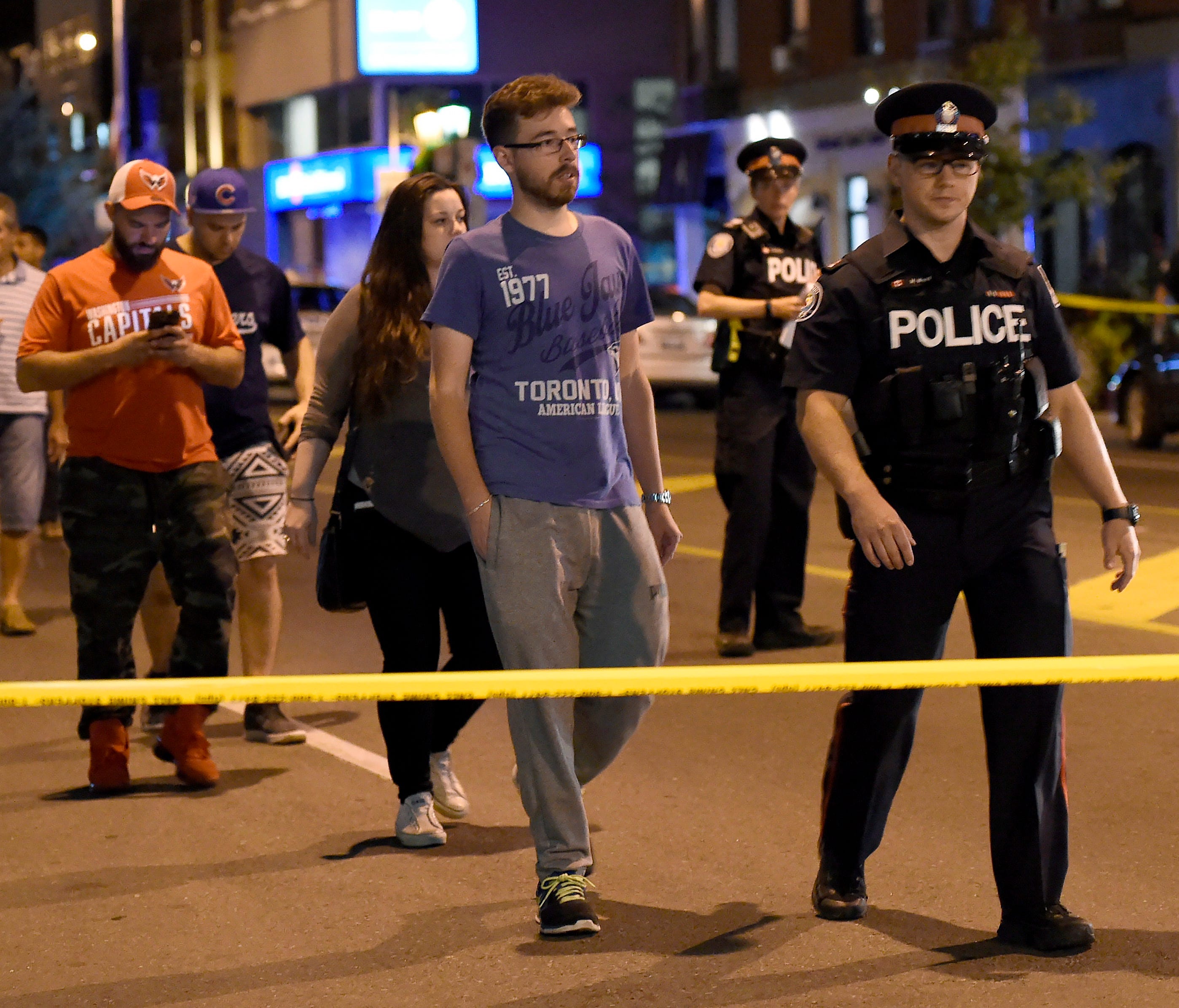 Civilians are escorted from the scene of a shooting in Toronto on Sunday.