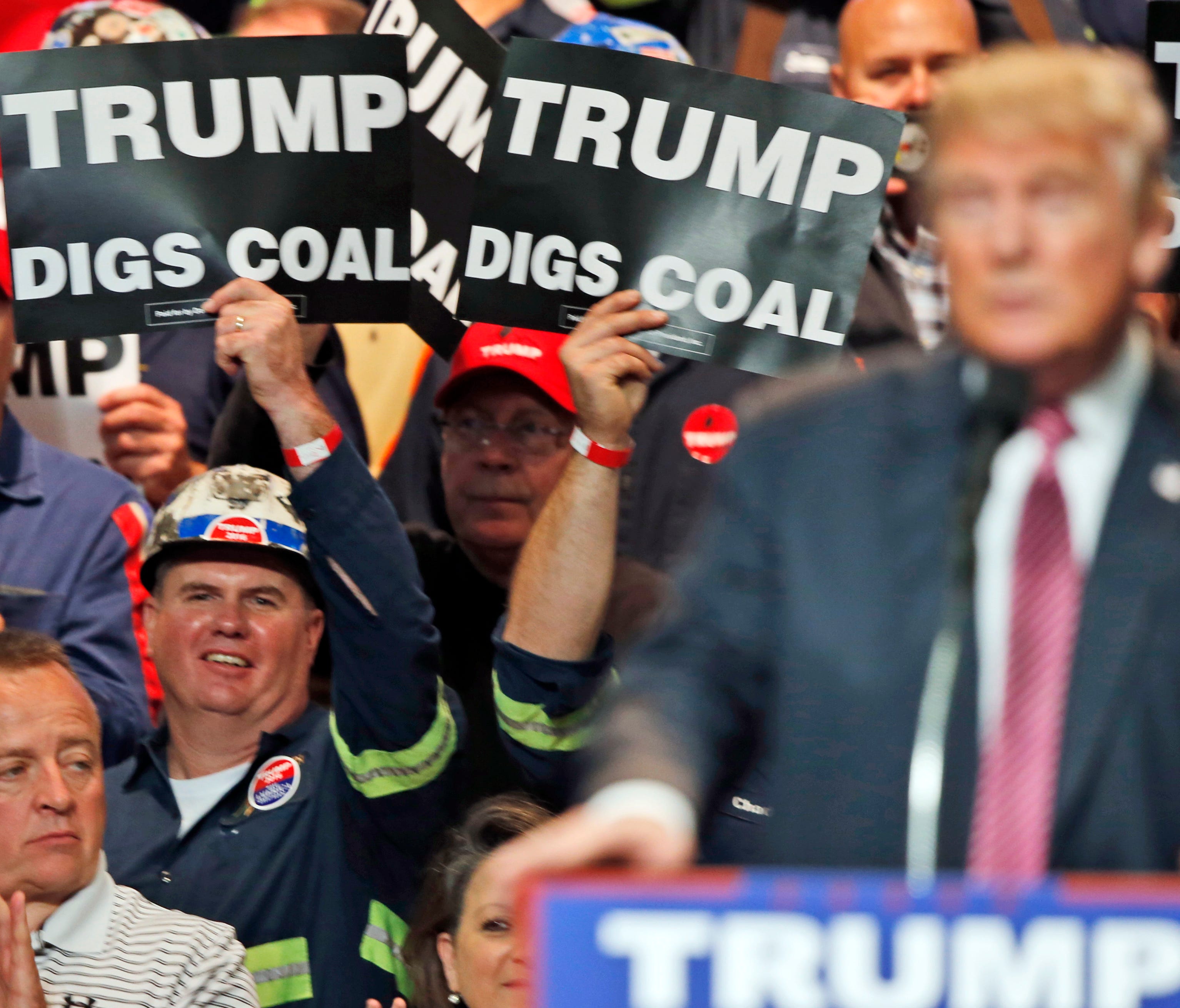 Coal miners wave signs as then-Republican presidential candidate Donald Trump speaks during a rally in Charleston, West Virginia on May 5, 2016.