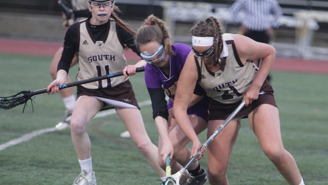 Clarkstown North's Nieve Donegan (purple)  battles for a ground ball against Clarkstown South's Maddie Buechli during a Section 1 girls lacrosse game between Clarkstown South and Clarkstown North at Clarkstown South High School Wednesday, May 4th, 2016. Clarkstown North won 13-12.