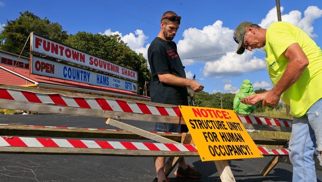 Cave City public works employees Ronnie Cline, right, and David Johnson prepare a barricade in the parking lot of Funtown Mountain Tuesday afternoon in Cave City, Ky. Code Enforcement officer Robert Smith said the gift shop and Wild West area were deemed unsafe for the public after electricity was shut off and reports of neglect on the property.  Sept. 8, 2015