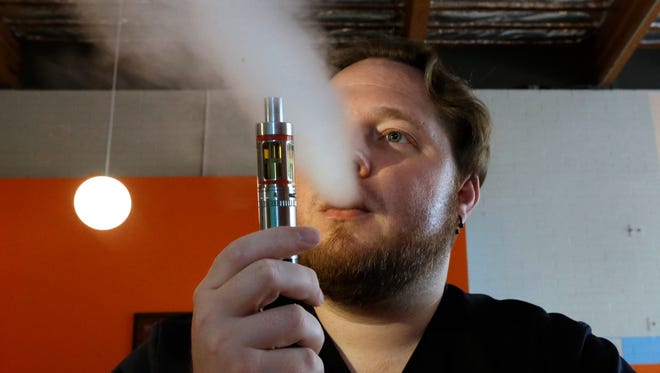 In this July 16, 2015, file photo, Bruce Schillin exhales vapor from an e-cigarette at the Vapor Spot, in Sacramento, Calif.