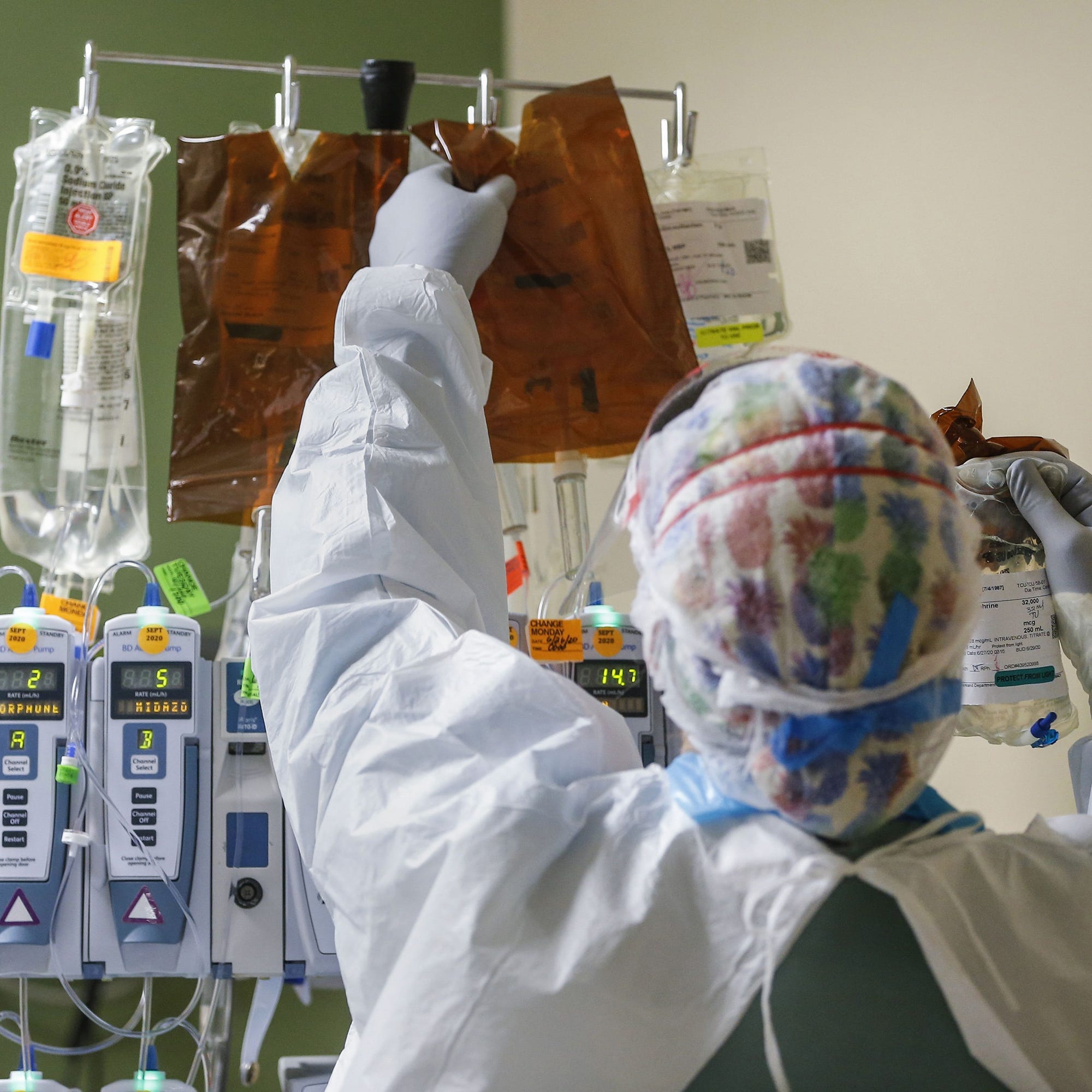 A healthcare worker changes out an intravenous drip while treating an intubated patient in the Parkland Hospital COVID-19 Tactical Care Unit on June 27, 2020, in Dallas.