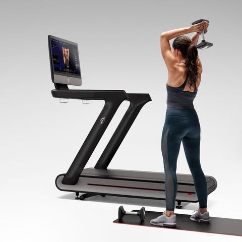 Woman standing next to a Peloton Tread+ and liftin