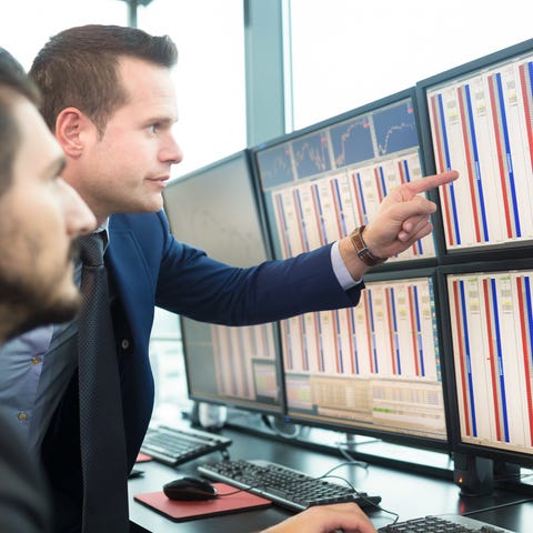 Two businessmen looking at financial data on scree