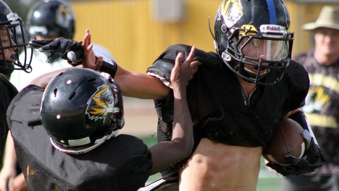 Hayz Hill, right, tries to break a tackle during practice Wednesday afternoon at Tiger Stadium.