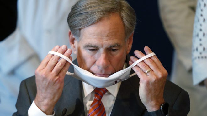 Gov. Greg Abbott puts on a mask during a news conference in Dallas on Aug. 6. Abbott on Thursday urged Texans not to let their guard down despite "COVID fatigue," noting that the state saw a spike in cases after Memorial Day weekend.