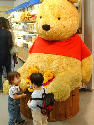 Two boys chat in front of a giant stuffed doll of Winnie-the-Pooh at the "World of Winnie-the-Pooh" exhibition at a Tokyo department store in this April 24, 2002 file photo. Officials in a Polish town have opposed a proposition to name a playground after Winnie-the-Pooh due to the bear's unclear gender and immodest clothing.