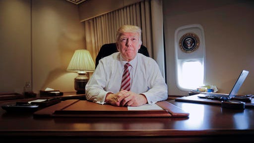 President Donald Trump sits at his desk on Air Force One upon his arrival at Andrews Air Force Base, Md., Thursday, Jan. 26, 2017.