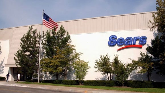 The exterior of a Sears department store with an American flag in front.
