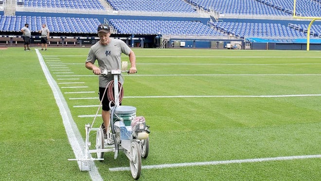 Former Veterans Memorial Park groundskeeper Tom Campione, a Little Falls native, applies paint to the football sideline while he and the rest of the Miami Marlins' grounds crew were preparing Marlins Park for a game between Florida International University and the University of Miami last November.