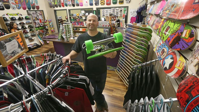Steve Hild, co-owner of Old Skull Skateboards, holds one of the hundreds of decks his shop offers at their new location at 2555 Baird Rd in Perinton on Oct. 30, 2015.