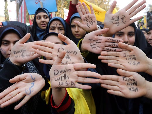 Students show their hands marked with anti-American. slogans outside the former U.S. embassy.