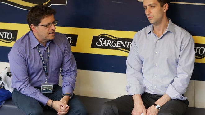 Milwaukee Brewers owner Mark Attanasio and general manager David Stearns talk in the dugout before a baseball game against the Cincinnati Reds Friday, Aug. 11, 2017, in Milwaukee. (AP Photo/Morry Gash)