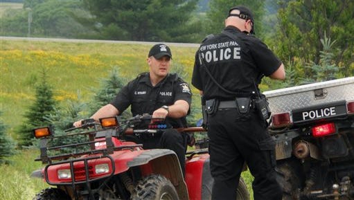 Authorities speak to one another during a search for two prisoners that escaped Clinton Correctional Facility two weeks prior, Saturday, June 20, 2015, in Allegany County, N.Y. The search for the two killers landed Saturday in New York's southern tier near the Pennsylvania border, about 350 miles from the prison where they escaped two weeks ago. New York State Police spokesman Beau Duffy said officers were investigating a possible sighting of the prisoners in Allegany County near the Pennsylvania border. (Kathryn Ross/The Wellsville Reporter via AP)