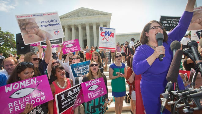 Kristin Hughs, right, announces to supporters  the Supreme Court's decision on the Hobby Lobby case in Washington, Monday, June 30, 2014. The Supreme Court says corporations can hold religious objections that allow them to opt out of the new health law requirement that they cover contraceptives for women.(AP Photo/Pablo Martinez Monsivais)