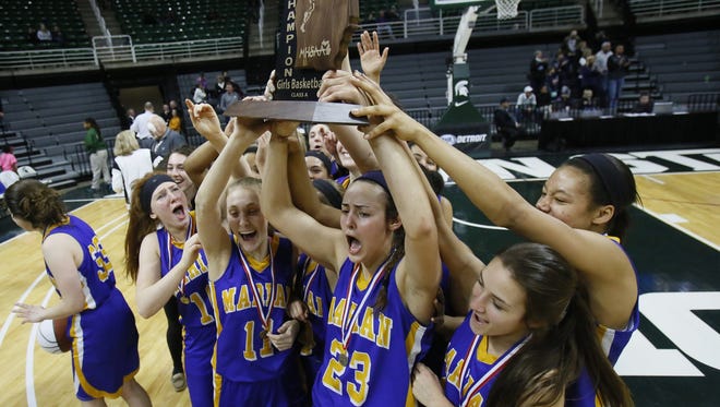Bloomfield Hills Marian players celebrate for the TV camera's with the championship trophy after their 51-37 win over Dewitt in Class A girls basketball final on March 21, 2015, in East Lansing.