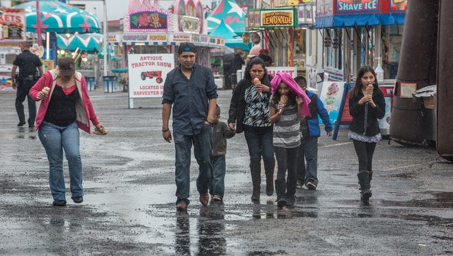 Families walk through wet fairgrounds looking for something to do. A very rainy day shut down many of the outdoor attractions at the Alabama National Fair on Sunday, Nov. 1, 2015, in Montgomery, Ala.