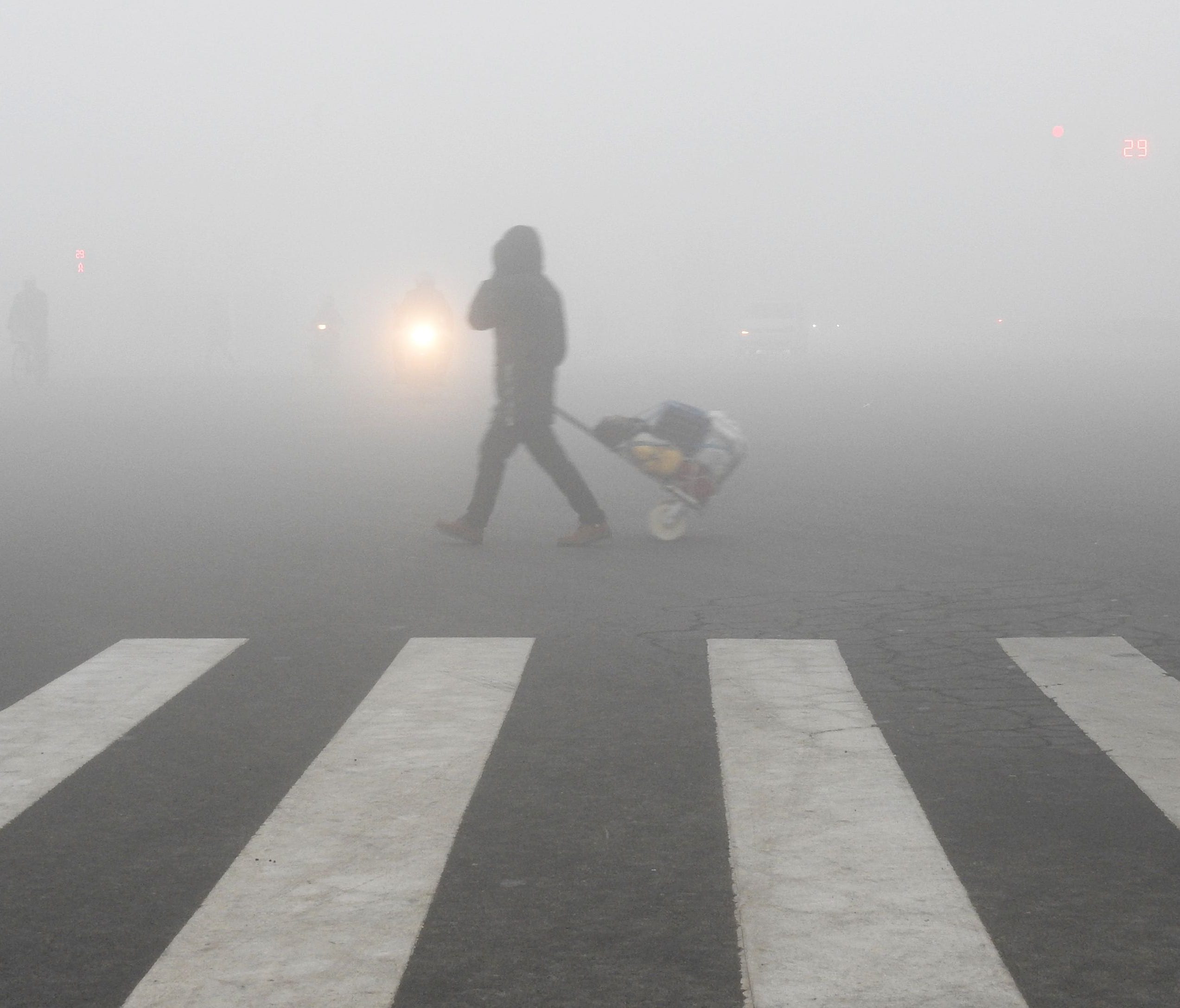 A pedestrian crosses a smog-shrouded street in Lianyungang, eastern China's Jiangsu province on December 19, 2016.