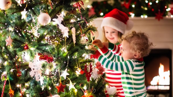 Happy little kids decorate a Christmas treee.