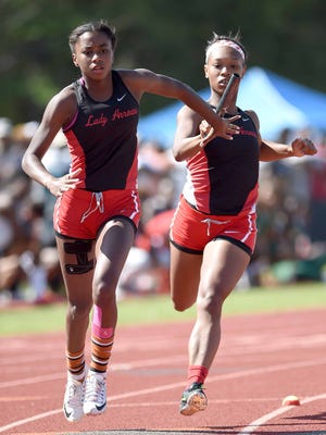Clinton's Dejah Miley (left) takes the handoff from second leg runner Justice Sims in the 4 x 200 meter relay on Friday at the MHSAA Class 2A-4A-6A State Track Championships in Pearl.