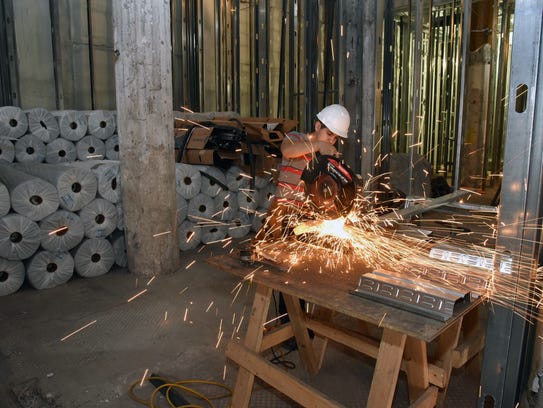 Construction worker Jose Orosco cuts steel framing