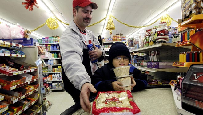 Tony Wells, left, of Des Moines buys dinner rolls and macaroni salad with his son, Cory, 6, on Christmas Day at Linn’s Super Market in Des Moines in a file photo.