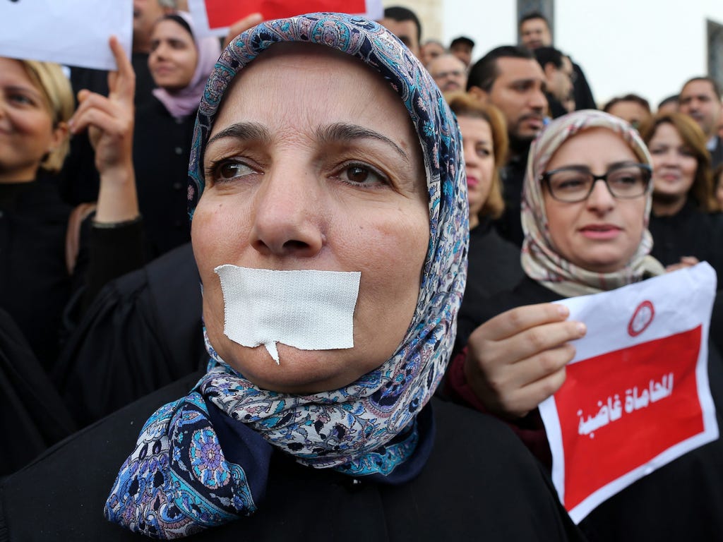 A lawyer with a sticker covering her mouth joins other lawyers during a demonstration against the draft budget that would include new taxes, in Tunis, Tunisia.