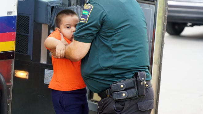A migrant boy released from federal custody gets help down from a bus by a private security guard in McAllen, Texas, on June 22, 2018.