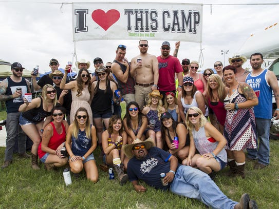 Festival-goers pose for a picture in front of a campsite
