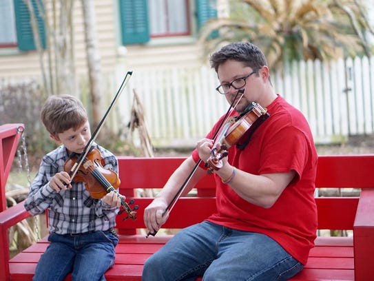 Owen Meche, left, receives fiddle tips from music teacher Brazos Huval.