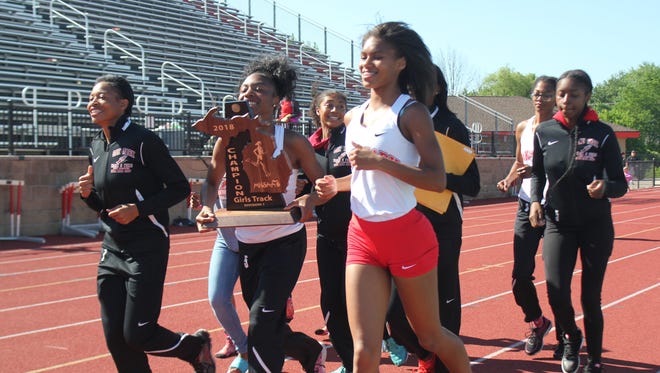 Oak Park's girls team finishes a victory lap with the trophy after winning its fourth Division 1 track and field state championship in five years.