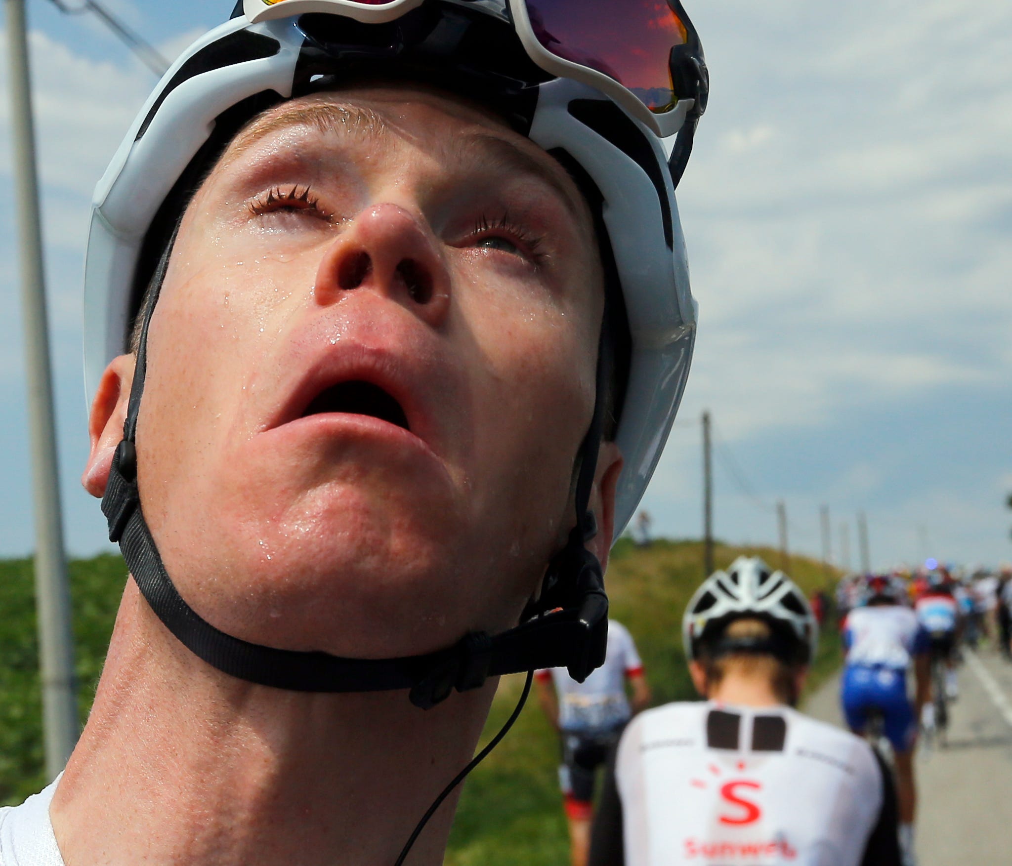 Britain's Chris Froome grimaces after he treated his eyes for tear gas or pepper spray sprayed on the peloton when a farmer's protest interrupted during the sixteenth stage of the Tour de France cycling race over 218 kilometers (135.5 miles) with sta
