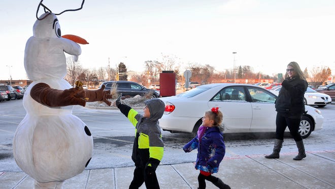 Ryan, left, and Adri Dallavalle, 5 and 3 respectively, run to give Salvation Army bell ringer Olaf (Brett Denman) a high-five as mom Kira Dallavalle takes a photo Friday, Dec. 18, at the Crossroads Center Macy's.