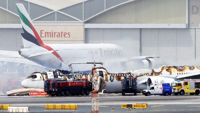 The burned remains of an Emirates airline Boeing 777 are seen in the foreground with an Emirates Airbus A380 visible in the background.